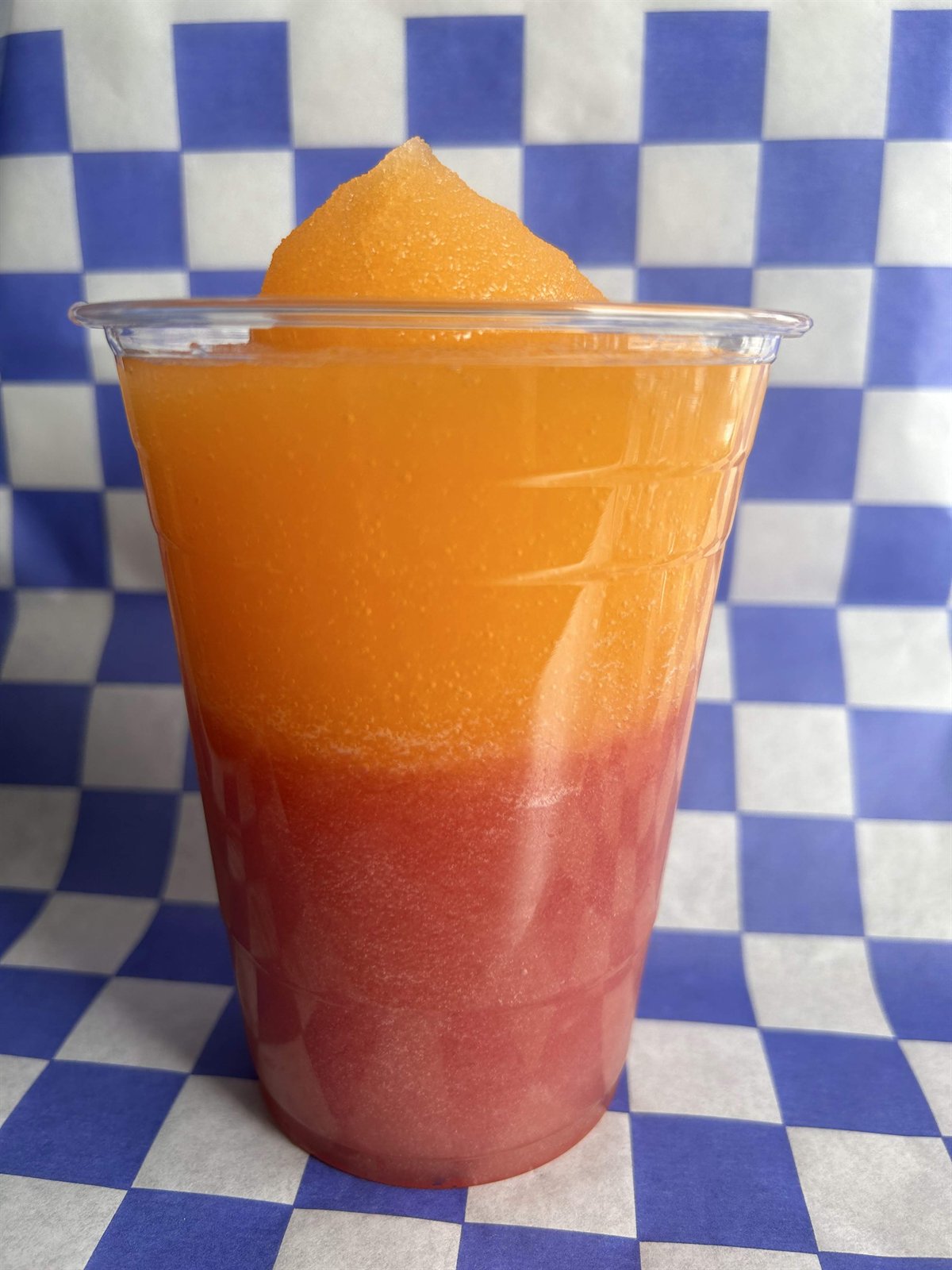 Medium frozen limeade layered orange and red in a clear cup