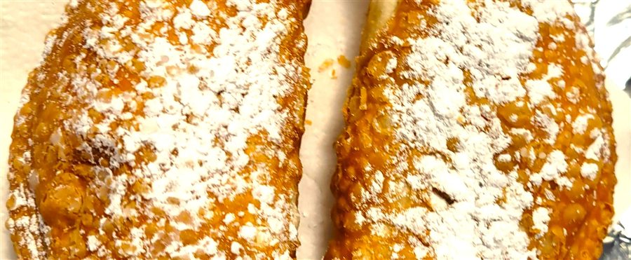 Two dessert empanadas dusted with powdered sugar