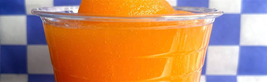 A frozen orange limeade in a clear cup on blue checkered paper